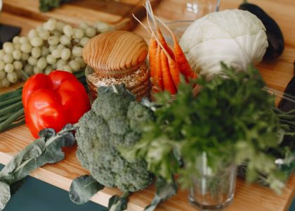 A vibrant display of fresh vegetables and fruits on a wooden board, including bell pepper, cabbage, and more.