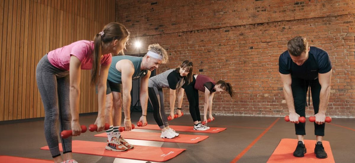 Fitness group performing exercises with dumbbells in a modern yoga studio setting.