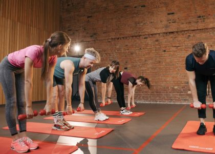 Fitness group performing exercises with dumbbells in a modern yoga studio setting.